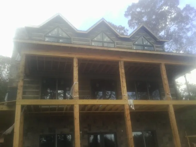 Dormers and porch framing on a large log home under construction — Roof Coating work by our crew in Bahama