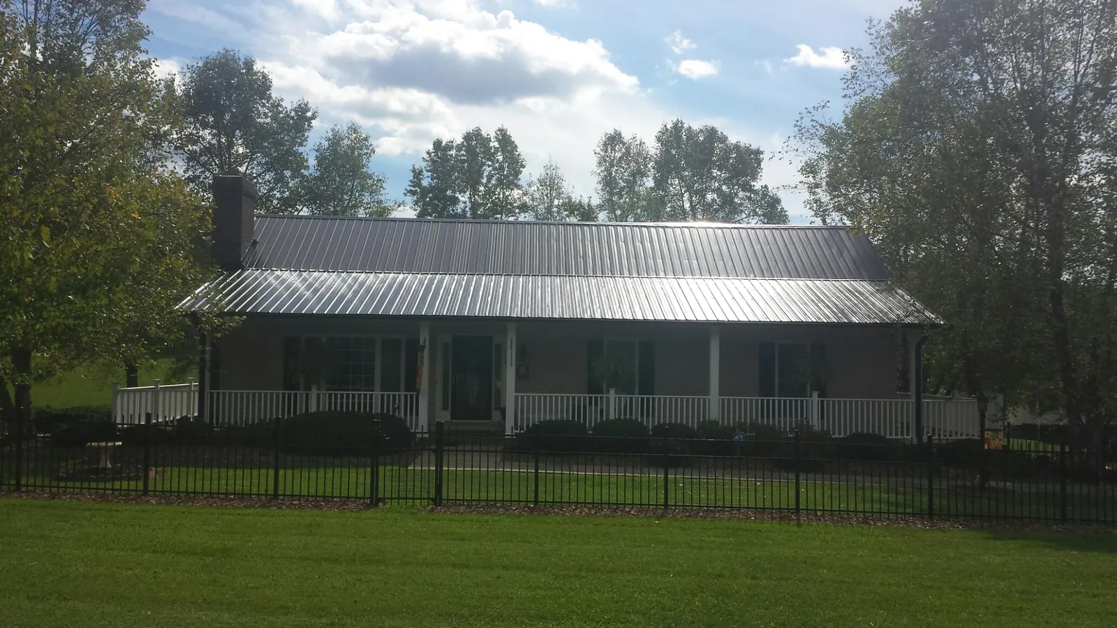 Gray metal roof on a brick ranch with a full width front porch — Gutter Guard Installation work by our crew in Bahama