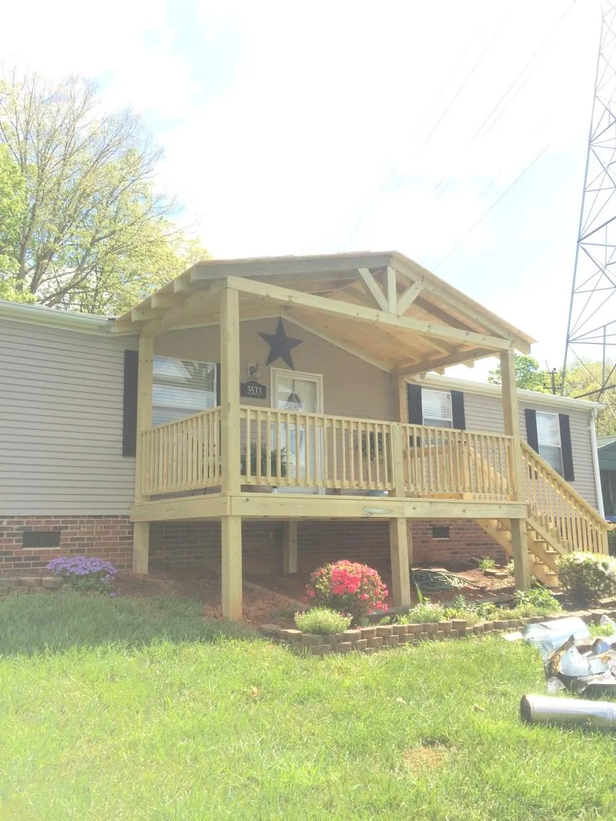 New gabled porch roof and deck railing added to a ranch home in Bahama