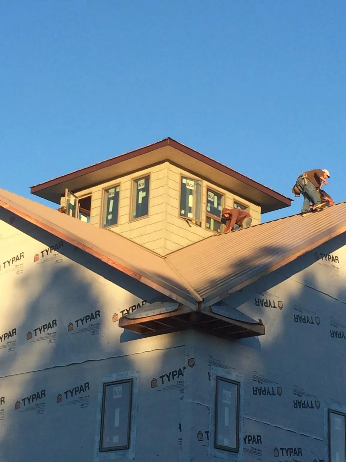 Roofers working around a rooftop cupola on a new metal roof at sunset — Roof Waterproofing in Bahama by Roofing Brothers